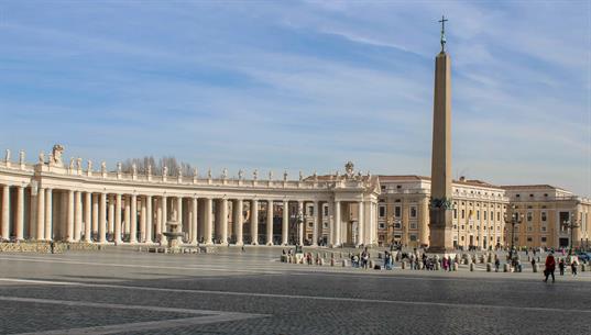 Blick auf den rechten Säulengang des Petersplatzes mit dem Obelisk, welcher ursprünglich aus Ägypten kam. Den ehemalige Abschluss des Obelisken bildete eine vergoldete Bronzeku-gel, die jedoch bei der Aufstellung auf dem Petersplatz durch ein Kreuz ersetzt wurde.